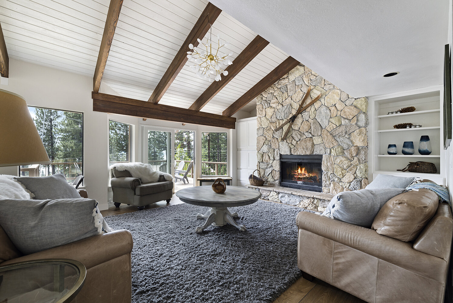 The great room at Kinpine House with its stone fireplace and vaulted beams, where a large group gathers